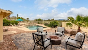 A backyard with a swimming pool, patio furniture, and a fire pit.