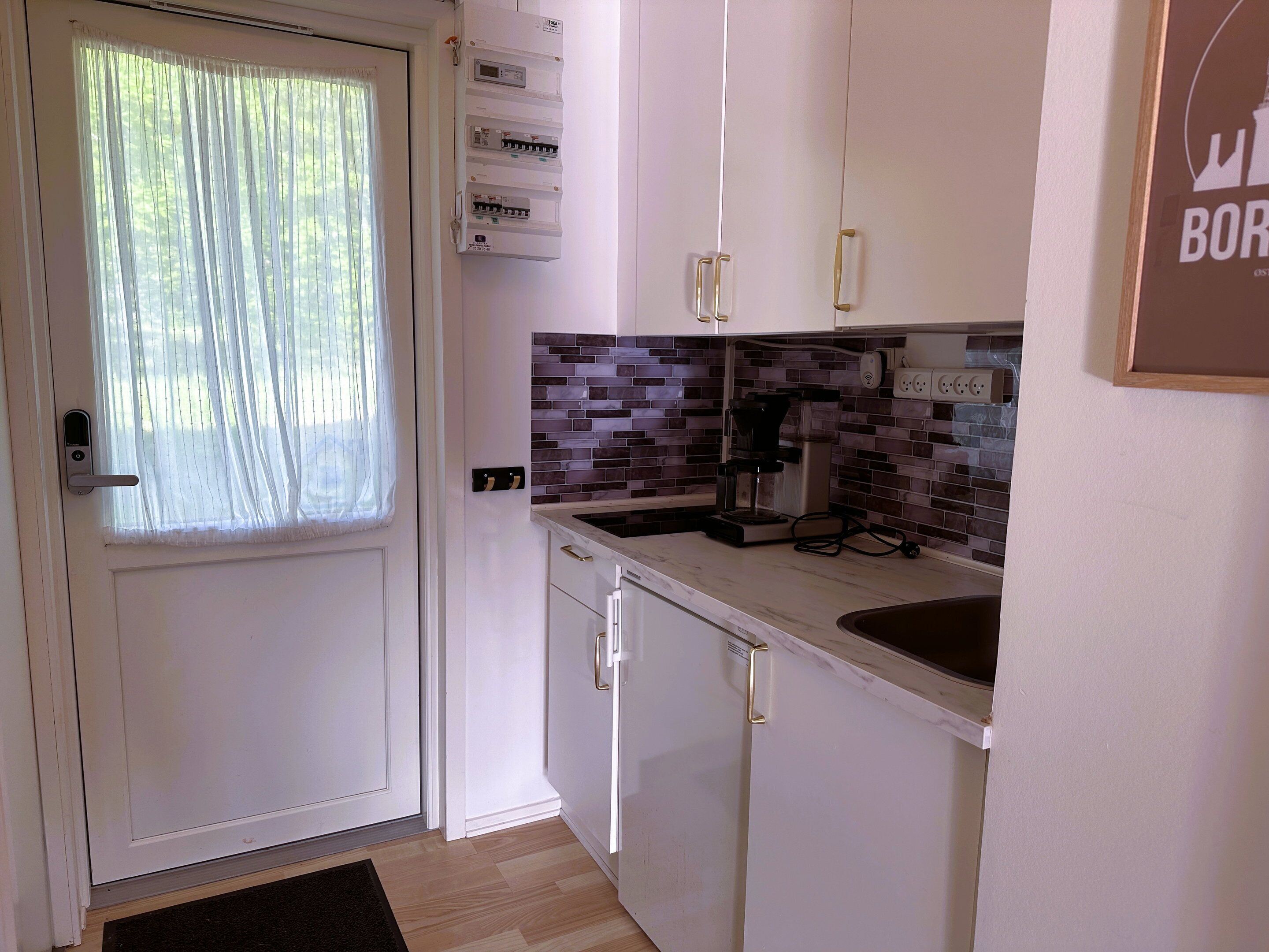 A kitchen with white cabinets, a coffee maker, and a tiled backsplash.