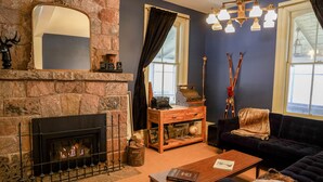 A cozy living room with a stone fireplace, a dark blue couch, and a wooden coffee table.