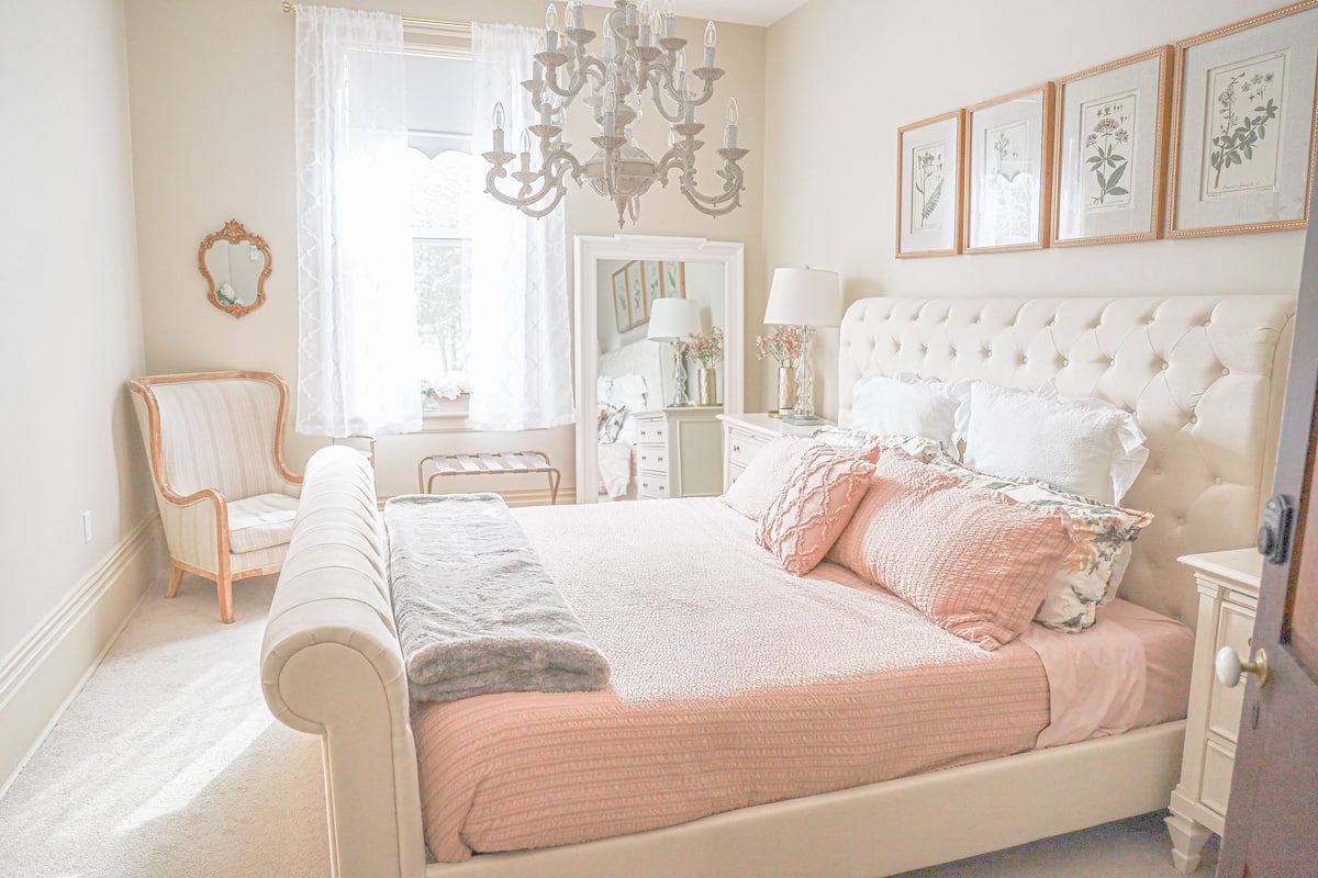 A bedroom with a large bed, a chair, a dresser, and a chandelier.