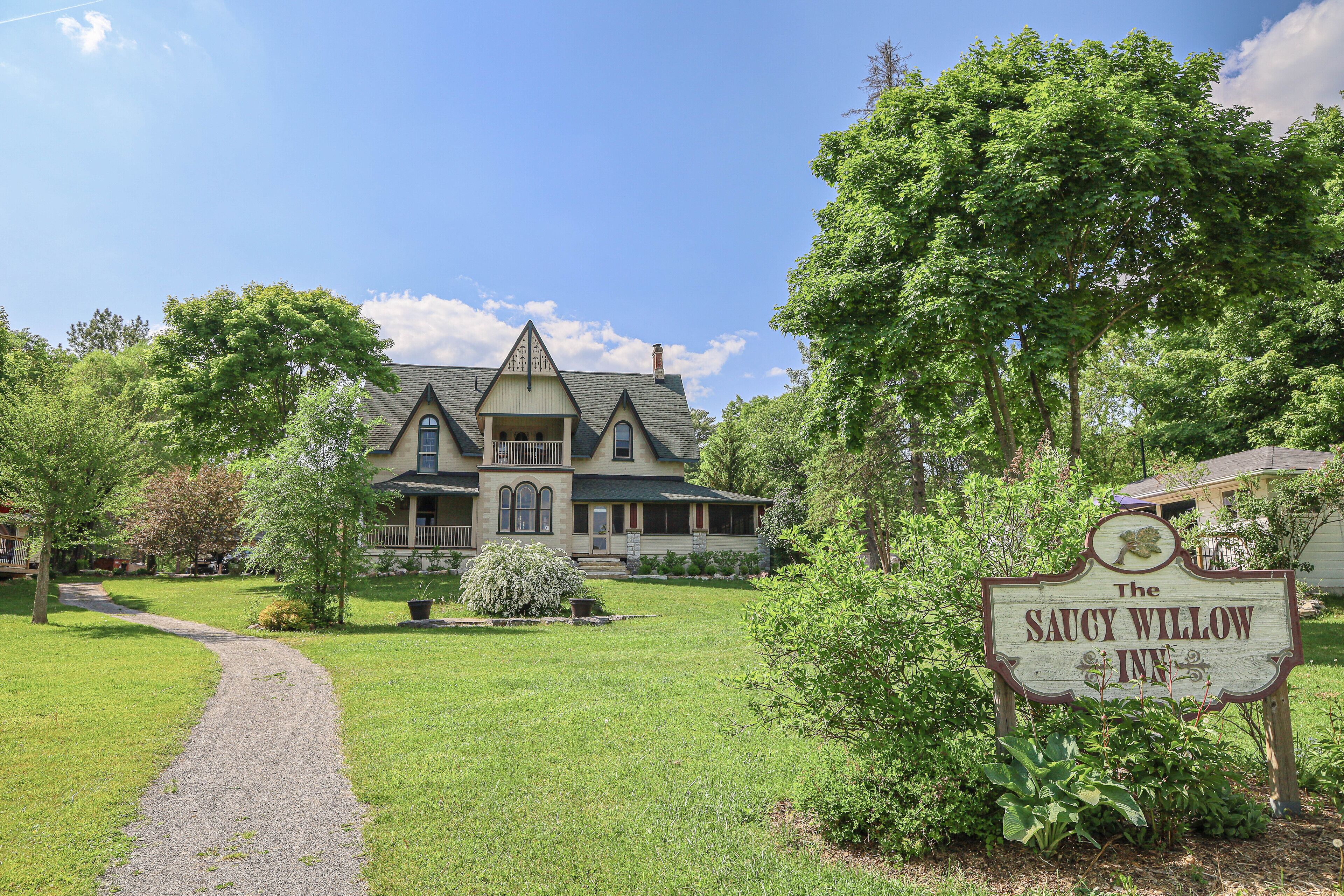 A large, historic house with a well-maintained lawn and a sign for The Saucy Willow Inn.