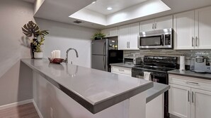 Una cocina moderna con armarios blancos, electrodomésticos de acero inoxidable y una isla central.