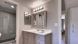 A bathroom with a vanity, a large mirror, and a shower area. - Charming & Comfy Condo in the Heart of Old Town! (Scottsdale)