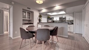 Una cocina moderna con armarios blancos, una isla central y una zona de comedor con una mesa redonda y sillas.