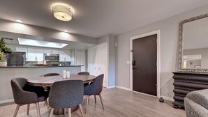 A modern kitchen with white cabinets, a microwave, and a dining area with a round table and chairs. - Charming & Comfy Condo in the Heart of Old Town! (Scottsdale)