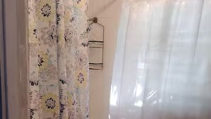 Een badkamer met een toilet, douchegordijn en een bad.