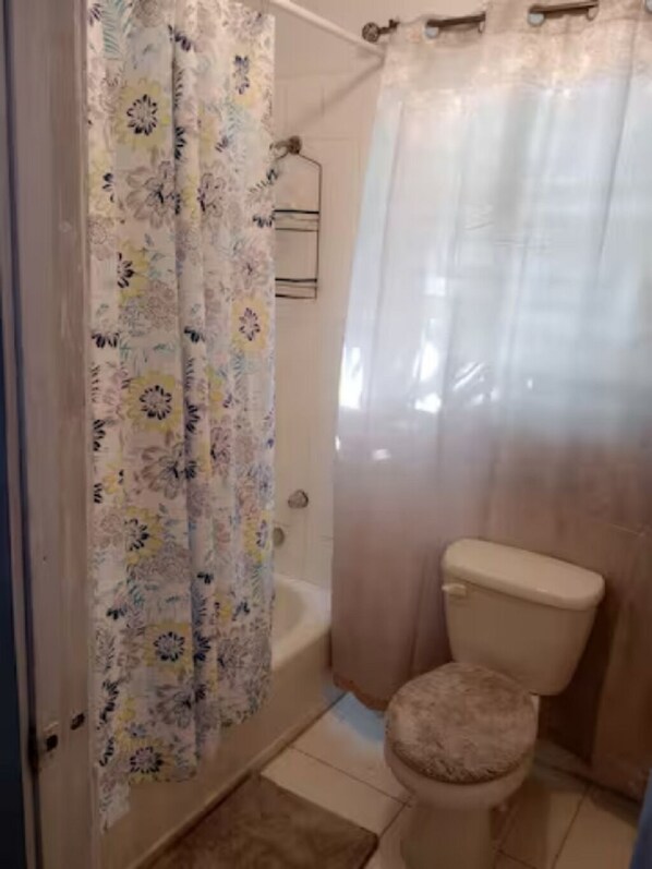 Un baño con inodoro, cortina de ducha y bañera.