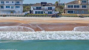 Una propietat a primera línia de platja amb diverses cases, un moll i una platja de sorra.