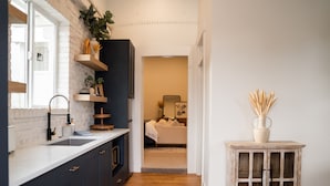 A modern kitchen with dark cabinets, a white countertop, and a wooden floor. There is a small cabinet with glass doors and a vase with reeds on top. - The Silo Inn near Zion, Snow Canyon and Bryce Canyon! honeymoon getaway. 2023 (Washington)