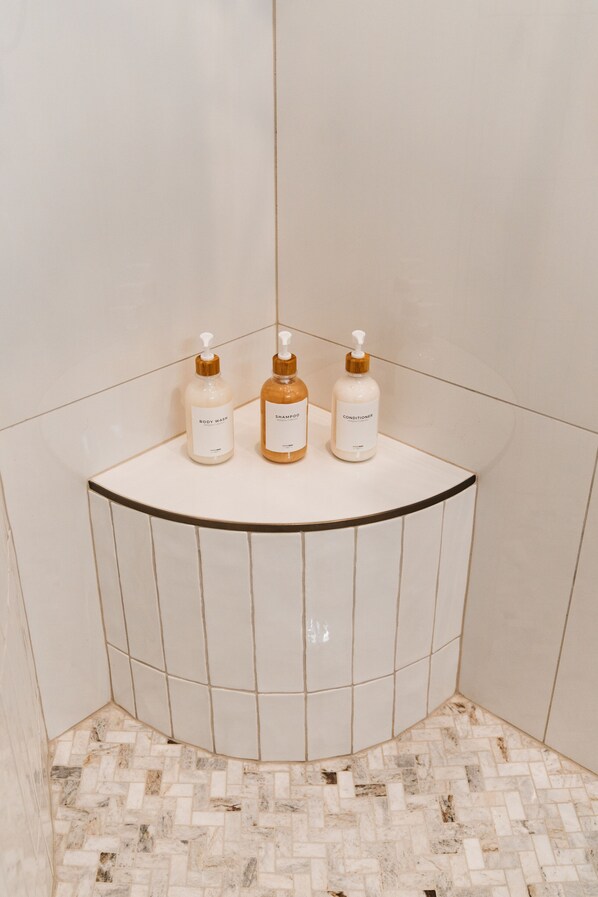 A bathroom with a white tiled wall and floor, a curved sink with three bottles of toiletries. - The Silo Inn near Zion, Snow Canyon and Bryce Canyon! honeymoon getaway. 2023 (Washington)