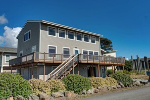 Ein zweistöckiges Gebäude mit einer Holzterrasse und Treppen, die zu einem überdachten Eingang führen.