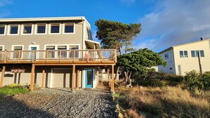 Een gebouw met twee verdiepingen, een balkon en een bord met de tekst 'Sandy Shores Retreat'.
