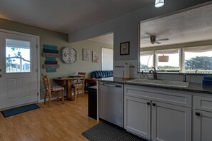 A kitchen with white cabinets, a built-in dishwasher, a granite countertop, and a window with a view.