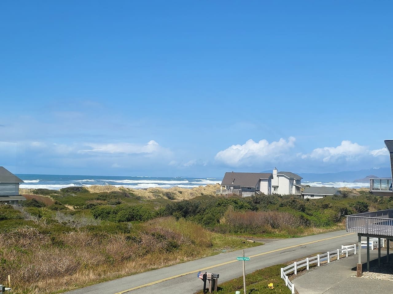 A coastal road with houses and a beach in the background.