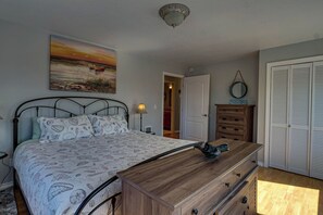 Ein Schlafzimmer mit Bett, Schminktisch, einem Gemälde, einer Tür und einem Schrank.