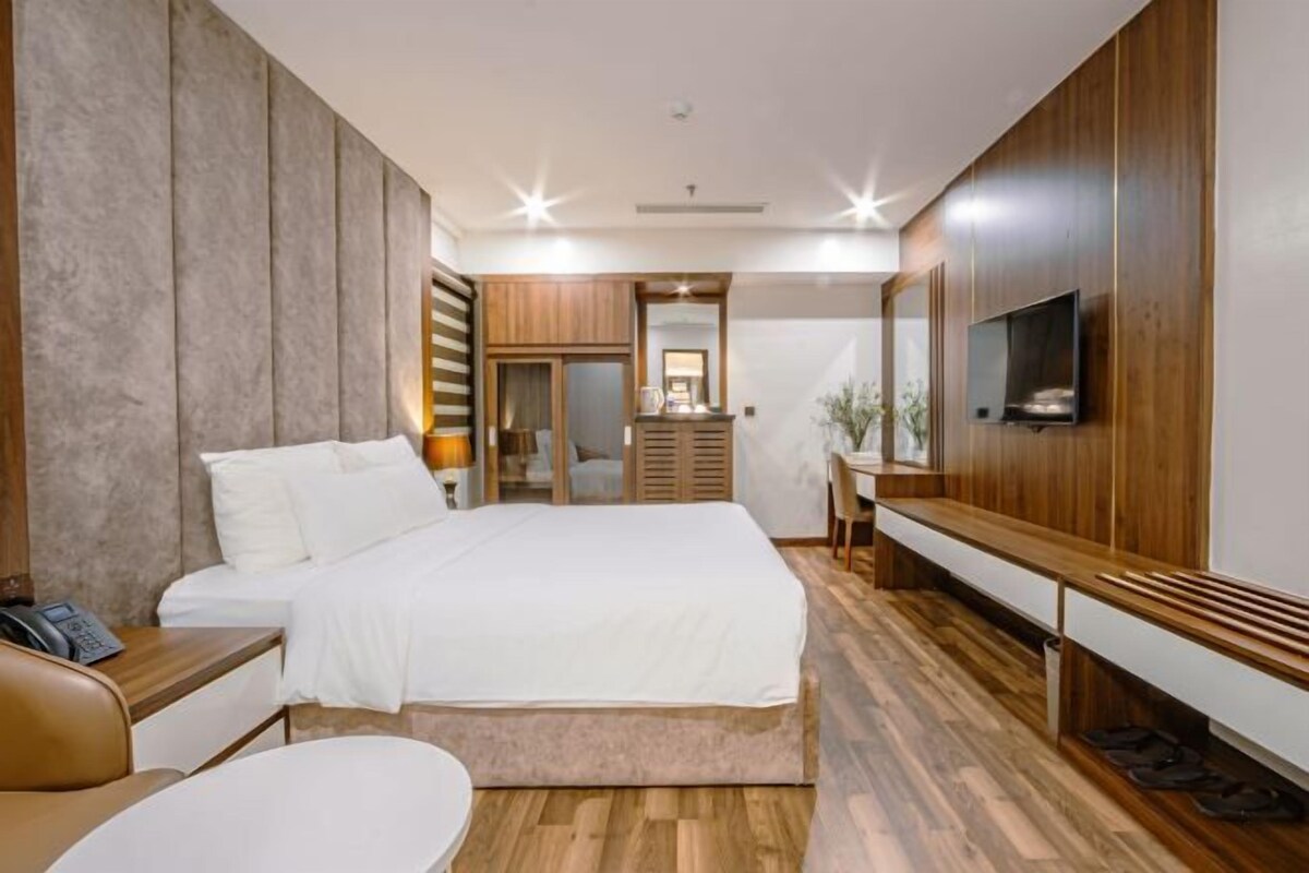 Une chambre moderne avec un grand lit, un lambris en bois, une télévision et un bureau avec une chaise.