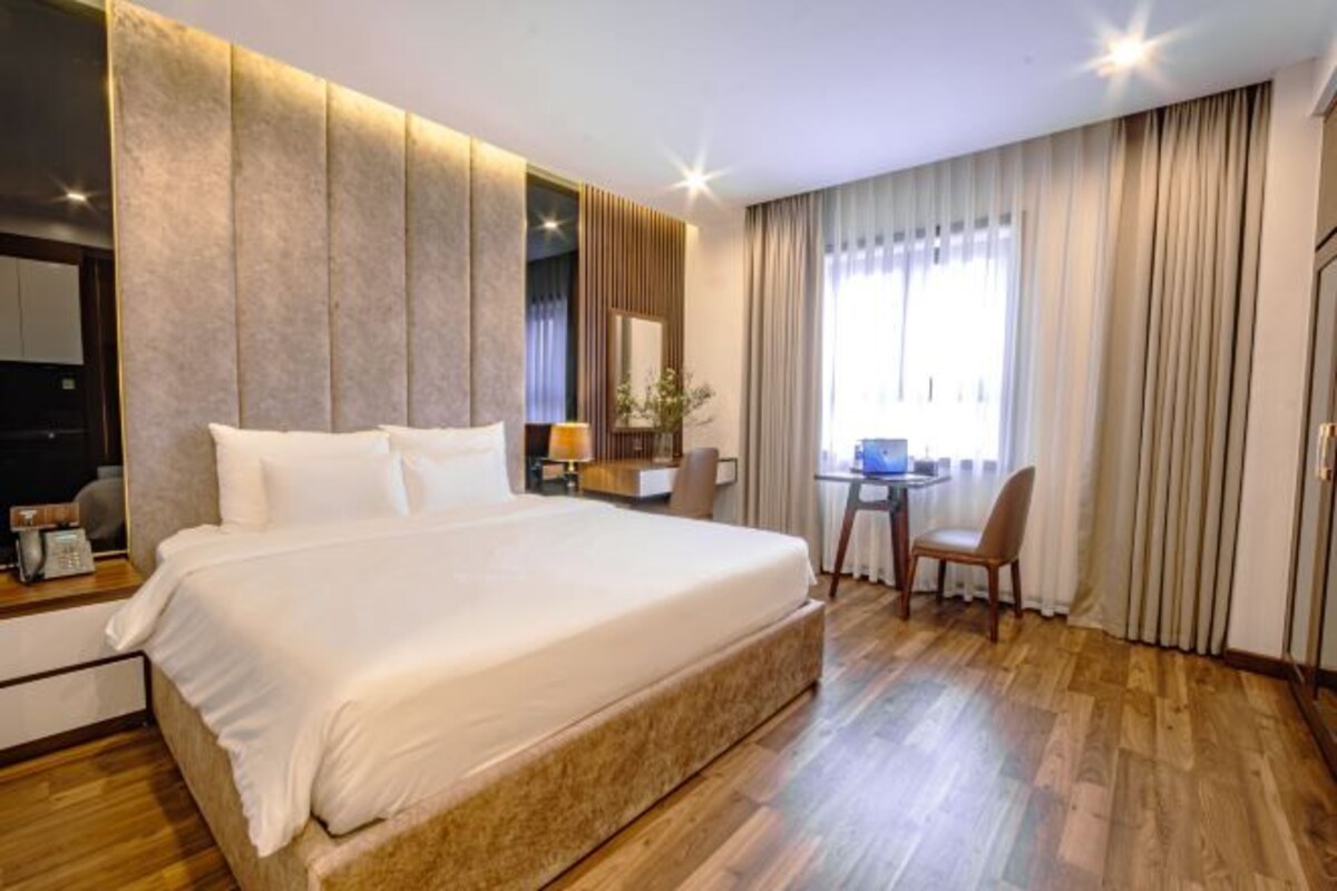 Une chambre d’hôtel avec un grand lit, un bureau et une chaise.