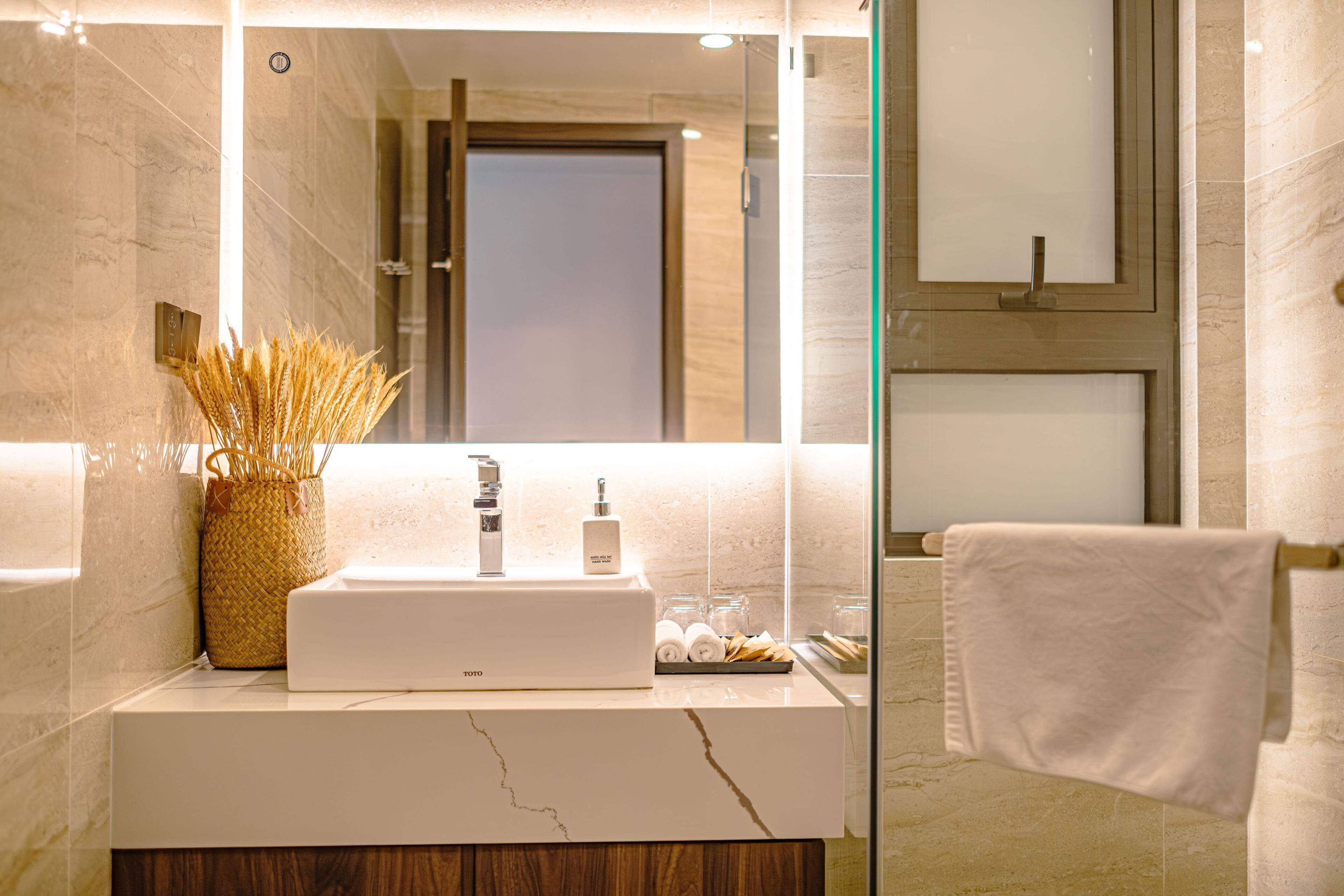 A modern bathroom with a marble sink, a glass shower enclosure, and a wooden vanity.