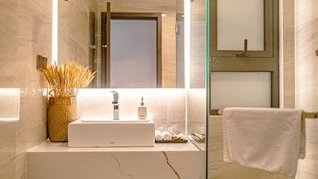 A modern bathroom with a marble sink, a glass shower enclosure, and a wooden vanity.