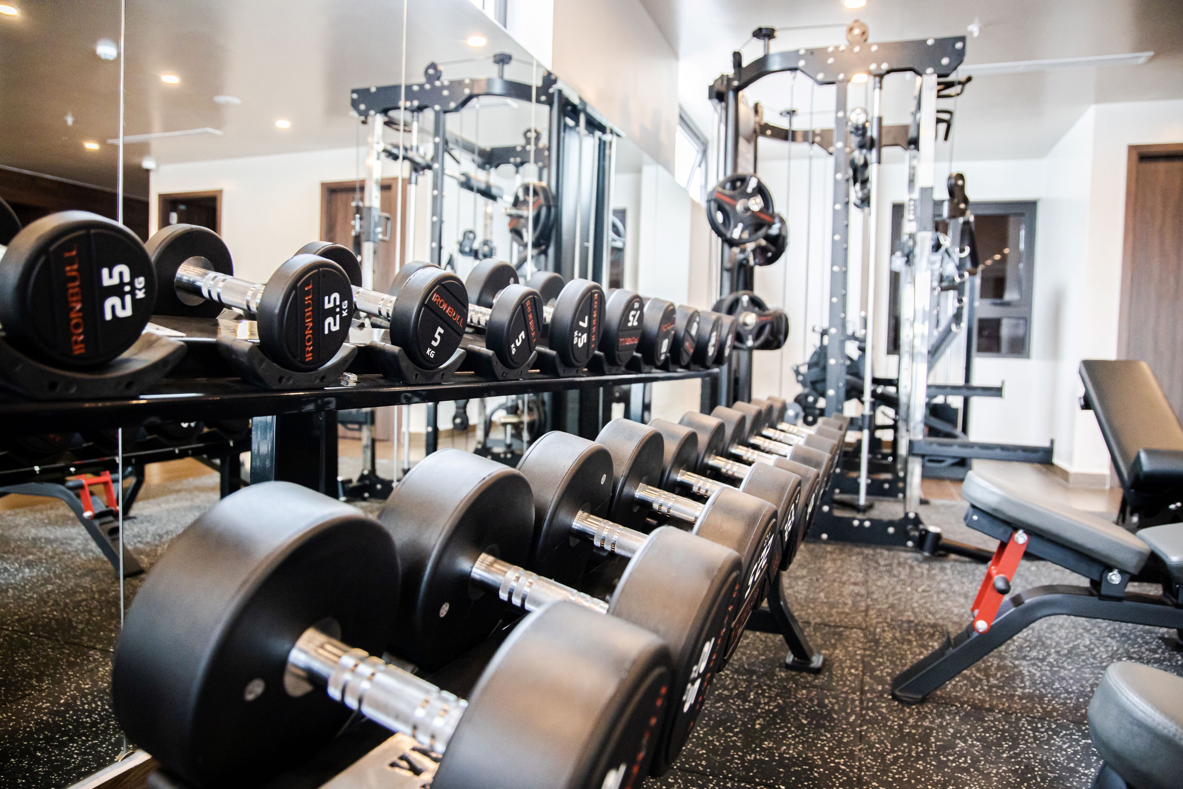 Et fitnessrum med rækker af håndvægte og træningsmaskiner.