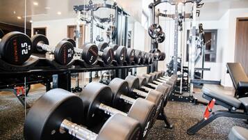 Et fitnessrum med rækker af håndvægte og træningsmaskiner.