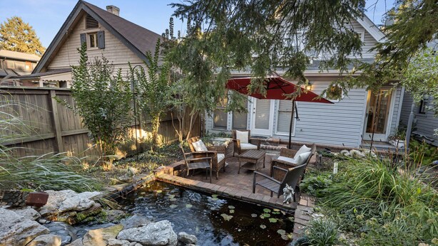 Ein Garten mit Teich, Terrassenmöbeln und einem Haus.