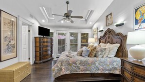 Ein Schlafzimmer mit einem großen Bett, einem hölzernen Schminktisch, einem Deckenventilator und Bildern an den Wänden.