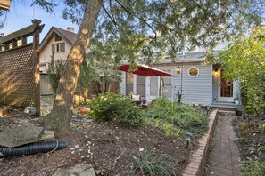 Une maison avec un jardin, un parapluie rouge et un chemin pavé de briques.