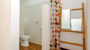 Un baño con inodoro, cortina de ducha estampada con lunares y espejo con marco de madera.
