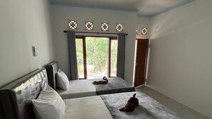 Un dormitorio con dos camas, un ventanal con cortinas y una puerta.