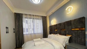 Un dormitorio moderno con una cama grande, una mesita de noche y un cabecero con iluminación integrada.