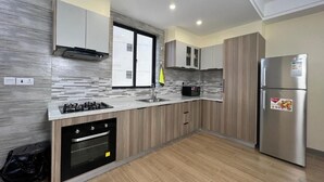Una cocina moderna con horno empotrado, refrigerador de acero inoxidable y ventana que proporciona luz natural.