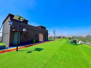 A modern building with a flat roof, solar panels, and a green lawn.