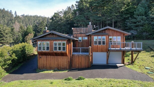 A two-story wooden cabin with a covered porch and a garage. - The ocean meets the meadow at the forest's edge. Private beach. Soak under stars (Manchester)