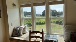 A room with a window seat, wooden chair, and pillows. - The ocean meets the meadow at the forest's edge. Private beach. Soak under stars (Manchester)