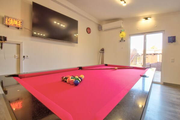 Une table de billard avec des billes, un téléviseur et une enseigne « Salon » dans une pièce offrant une belle vue.