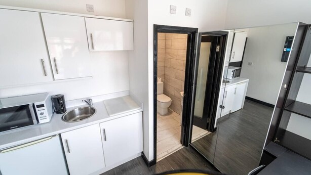 A modern kitchen with white cabinets, a microwave, a sink, and a refrigerator. - Stunning studio next to restaurants! (Birmingham)