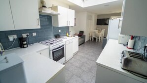 A compact kitchen with a gas stove, oven, and a small dining area with a table and chairs. - Modern Studio next to University of Birmingham (Birmingham)