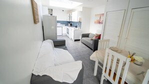 A compact living space with a kitchenette, a sofa, a dining table, and a chair. - Modern Studio next to University of Birmingham (Birmingham)