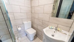 Un baño con inodoro, lavamanos y cabina de ducha de vidrio.