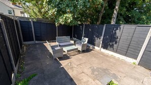 Un patio trasero con zona de estar, que incluye un espacio para sentarse y una pequeña mesa.