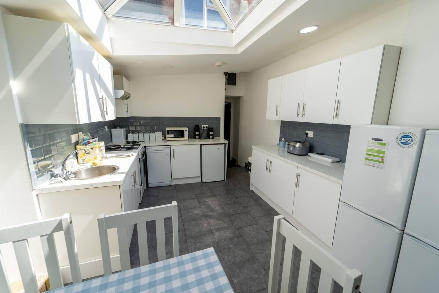 A compact kitchen with white cabinets, a microwave, a stove, and a refrigerator.