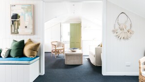 A bright, modern living room with a blue sofa, wicker ottoman, and a large abstract painting. - Barrenjoey House  (Palm Beach)