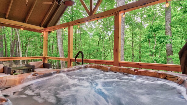 A hot tub in a wooden cabin with a view of a forest. - Bamby Bungalow. Family and Pet Getaway. Fenced in yard and minimal stairs (Ellijay)