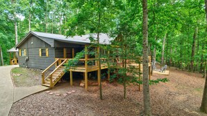 A cabin with a wooden deck, a staircase, and a covered outdoor area. - Bamby Bungalow. Family and Pet Getaway. Fenced in yard and minimal stairs (Ellijay)