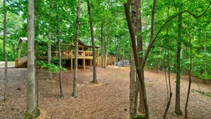 A wooden cabin with a deck and outdoor seating area surrounded by trees. - Bamby Bungalow. Family and Pet Getaway. Fenced in yard and minimal stairs (Ellijay)