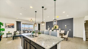 A modern kitchen with a granite countertop, dark cabinetry, and pendant lighting. - 9Br/6Ba lake view Pool House from 330/NT, Close To Disney (Kissimmee)