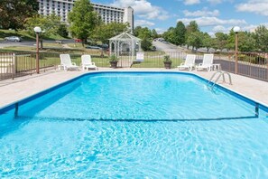 Relax by the pool surrounded by lush greenery and a shaded gazebo.