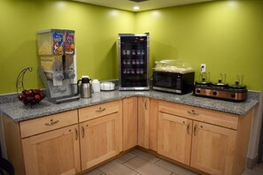 Kitchen area with a granite countertop, coffee maker, toaster, microwave, and two refrigerators.