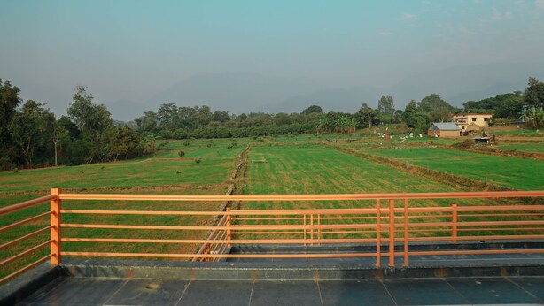 A rural landscape with fields, a small building, and a bridge. -  KK Jungle View Resort Jim Corbett (Kaladhungi)
